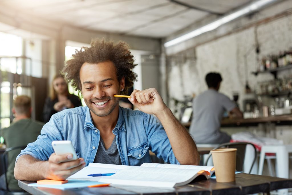 image of male student working at cafeteria doing his home assigment