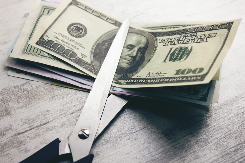 image of scissor cutting dollar bills