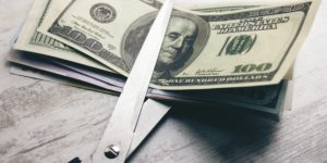 image of scissor cutting dollar bills
