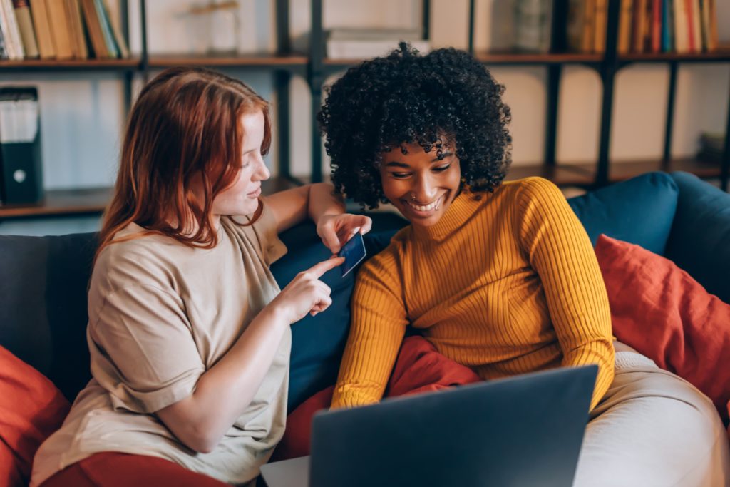 two friends using discount card on laptop