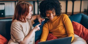 two friends using discount card on laptop